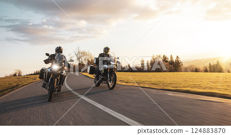 Two Drivers Riding Motorcycle on Empty Road During Sunset. Two Drivers Riding Motorcycle on Empty Road During Sunset. 124883870