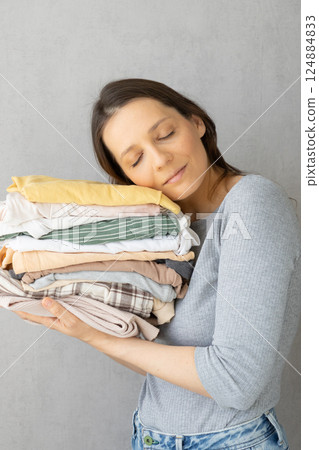 Laundry, woman holds stack of clothes in her hands after dry cleaning. housework, cleaning ironing.  124884833