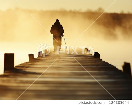 Fisherman walking on wooden pier through morning mist Fisherman walking on wooden pier through morning mist 124885644