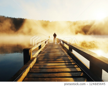 Man fishes on wooden pier at sunrise 124885645
