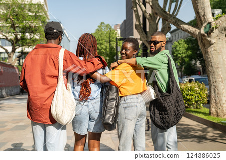 Rearview black college friends meet up downtown, embracing before group hangout and turn to camera Rearview black college friends meet up downtown, embracing before group hangout and turn to camera 124886025
