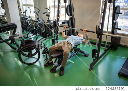 Disabled athlete strengthens body by lifting barbell in gym, healthy sports for physical progres 124886191