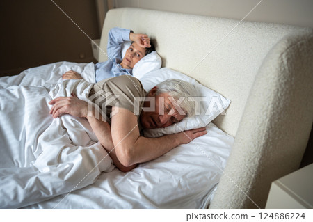 Upset angry wife lies in bed after argument watching husband who fell asleep ignoring conflict 124886224