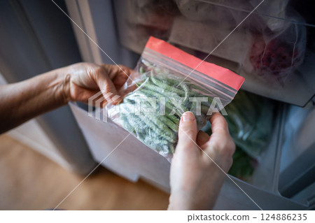 Hands with green beans from freezer in zip bag. Winter storage, fresh healthy homemade meal cooking 124886235