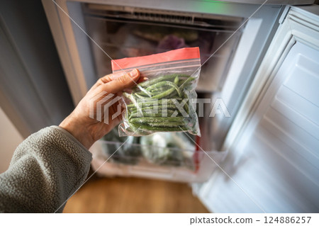 Hands with green beans from freezer in zip bag. Winter storage, fresh healthy homemade meal cooking 124886257
