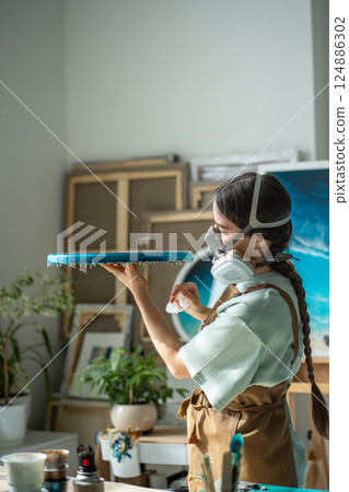 Serious professional female artist examine epoxy resin project on round board post dry in workshop  124886302