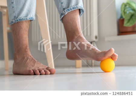 Man massaging arthritic feet with ball at home Man massaging arthritic feet with ball at home 124886451