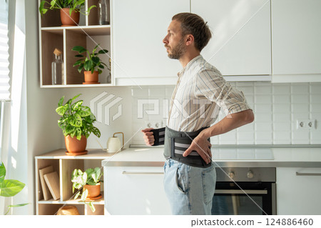 Man wearing back support corset on lower back to treatment of hernia, relieve stress on spine. Man wearing back support corset on lower back to treatment of hernia, relieve stress on spine. 124886460
