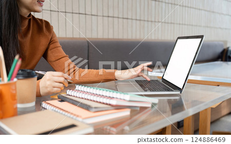Study and Focus. A student engages with her laptop in a scholarly cafe environment filled with notes and books. Study and Focus. A student engages with her laptop in a scholarly cafe environment filled with notes and books. 124886469