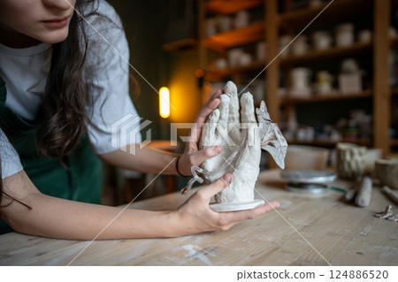 Glassblower forming glass flower in clay hand design for decor production. Contemporary art business Glassblower forming glass flower in clay hand design for decor production. Contemporary art business 124886520