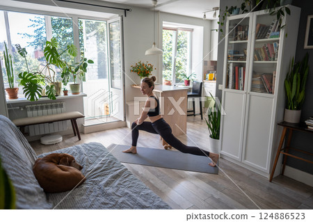Determined woman do fitness leg lunges, stretching as morning habit. Daily healthy exercise with dog Determined woman do fitness leg lunges, stretching as morning habit. Daily healthy exercise with dog 124886523