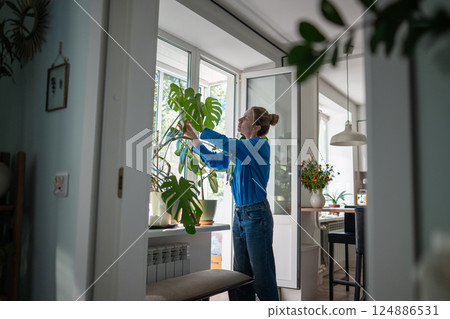 Woman examine plant leaves closely for signs of disease and dust, foliage cleaning, pest control 124886531