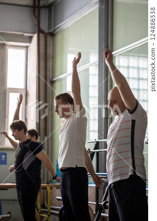 Fit male athletes rowers warm up muscles, wish circular arm movements before working out at the gym Fit male athletes rowers warm up muscles, wish circular arm movements before working out at the gym 124886538