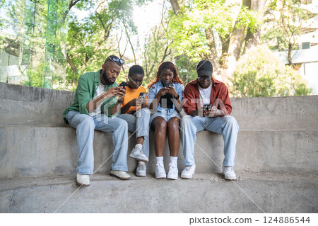Black guys in park hang in smartphones, browse social media, chatting. Youth dependency on gadgets Black guys in park hang in smartphones, browse social media, chatting. Youth dependency on gadgets 124886544