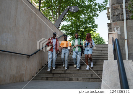 Group of thoughtful African American friends enthusiastically discuss various topics, walk outdoors Group of thoughtful African American friends enthusiastically discuss various topics, walk outdoors 124886551