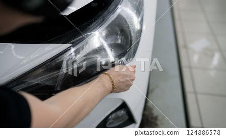 Professional car wrapper applying vinyl film on vehicle 124886578