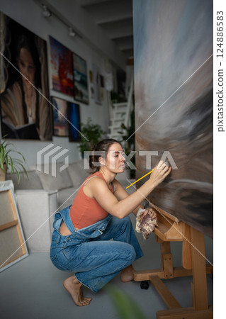 Professional female artist in light art studio painting picture. Portrait of creative woman painter. Professional female artist in light art studio painting picture. Portrait of creative woman painter. 124886583