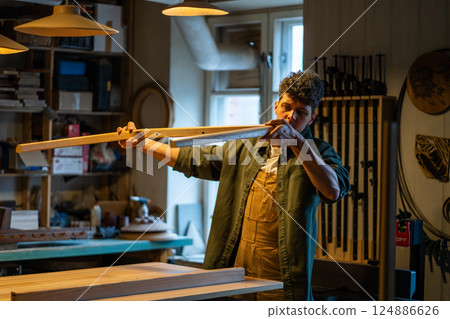 Craftsman inspects table legs and base, ensuring even surfaces and quality construction in workshop 124886626