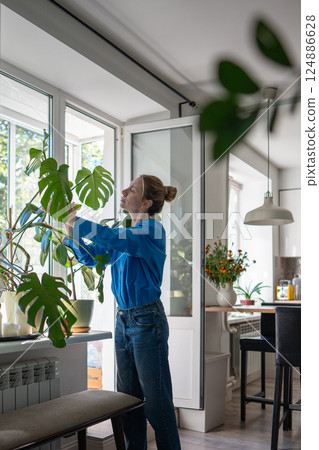 Woman examine plant leaves closely for signs of disease and dust, foliage cleaning, pest control 124886628