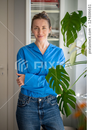 Calm happy woman standing close to mini garden by monstera leaves at home or office, plant care Calm happy woman standing close to mini garden by monstera leaves at home or office, plant care 124886681