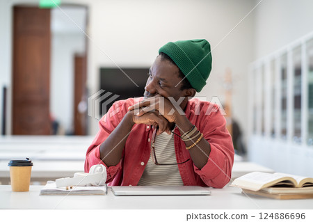 Serious African American student man tired of studying after learning difficult homework on laptop.  124886696