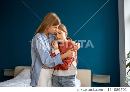 Affectionate empathic young mom tender embracing calming sad upset teen daughter. 124886701