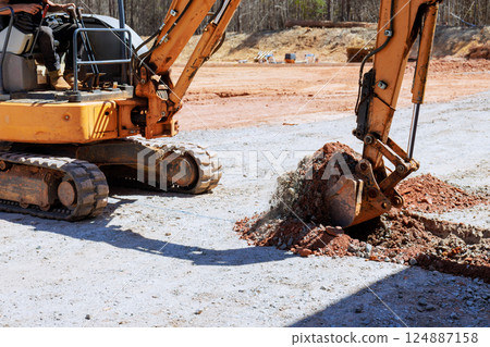 Heavy machinery excavator to digs trench at construction site 124887158