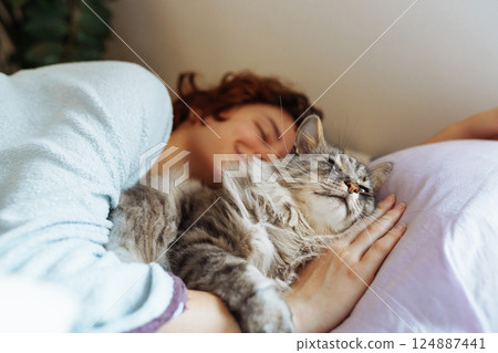 sleeping young woman on bed with pet cat sleeping young woman on bed with pet cat 124887441