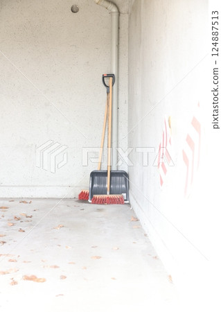 A broom is leaning against a wall in a room A broom is leaning against a wall in a room 124887513