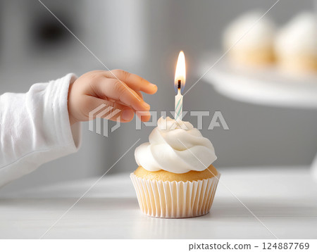 Baby's hand reaching for a cupcake with a lit candle Baby's hand reaching for a cupcake with a lit candle 124887769