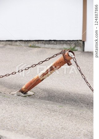 A rusty chain is attached to a metal pole 124887866
