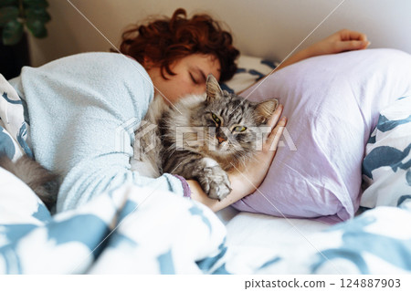 sleeping young woman on bed with pet cat 124887903