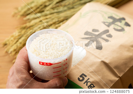 男手拿著一袋米和一個量杯 男手拿著一袋米和一個量杯 124888075