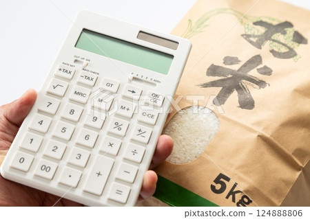 Hand holding a bag of rice and a calculator 124888806