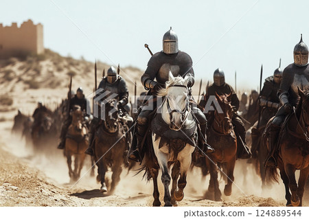 Knights on horseback charge through a desert landscape towards a distant fortress in the crusades 124889544