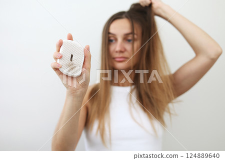 Hair loss problem. Worried young woman shows hairbrush with bunch of fallen hair after combing. Postpartum period, menstrual or endocrine disorder, hormonal disbalance, stress concept. Selective focus Hair loss problem. Worried young woman shows hairbrush with bunch of fallen hair after combing. Postpartum period, menstrual or endocrine disorder, hormonal disbalance, stress concept. Selective focus 124889640