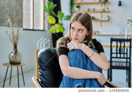 Sad unhappy thoughtful young woman sitting in armchair at home 124889698
