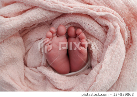 Baby foot on pink soft coverlet, blanket.Close-up of tiny, cute, bare toes, heels and feet of a newborn girl, boy.Detail of a newborn baby legs. Macro horizontal professional studio photo.  124889868
