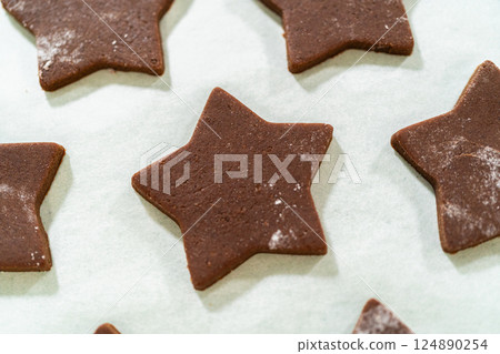 Close-up view of raw chocolate star cookies placed on parchment paper, highlighting their clean edges. Close-up view of raw chocolate star cookies placed on parchment paper, highlighting their clean edges. 124890254