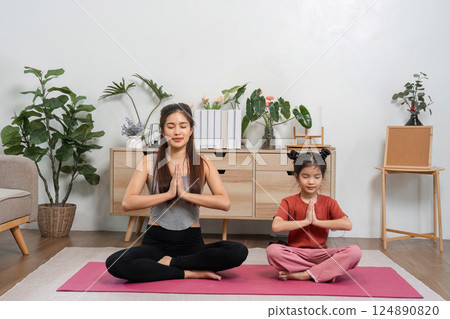 Yoga and Mindfulness. A mother and daughter sitting in meditation pose, enjoying moments of tranquility together. Yoga and Mindfulness. A mother and daughter sitting in meditation pose, enjoying moments of tranquility together. 124890820