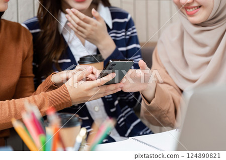 Sharing and Collaboration. Friends enjoy a smartphone moment while deep in conversation over coffee. 124890821