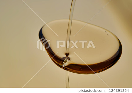 Texture of pouring cosmetic oil on a golden background. 124891264