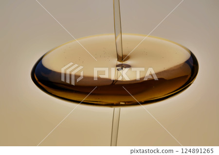 Texture of pouring cosmetic oil on a golden background. 124891265