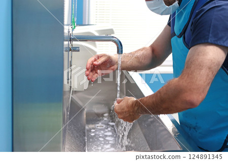 Male surgeon washes his hands before surgery. Water is pouring from faucet. Doctor's hands. Concept of healthcare. 124891345