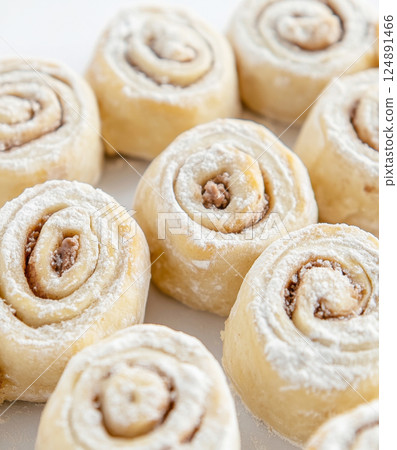 Cinnamon rolls made from dough, sprinkled with flour on white surface Cinnamon rolls made from dough, sprinkled with flour on white surface 124891466