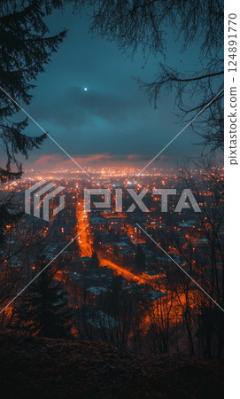 Bright city lights illuminate the valley below at night from a forest trail 124891770
