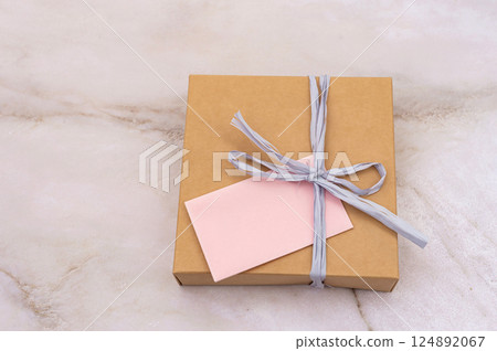National Cartonnage Day. Wrapped Gift Box with Pink Note on Marble Background National Cartonnage Day. Wrapped Gift Box with Pink Note on Marble Background 124892067