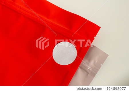 White circular sticker on red poly mailer envelope with natural shadow. White circular sticker on red poly mailer envelope with natural shadow. 124892077