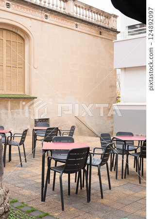 Outdoor cafe seating area with empty tables and chairs in an urban patio setting Outdoor cafe seating area with empty tables and chairs in an urban patio setting 124892097