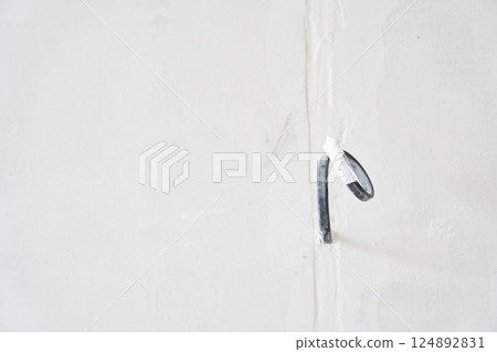 A close-up of electrical wires protruding from a white wall. Electrical work during the renovation of the apartment. Electric cable in a new apartment. High quality photo 124892831